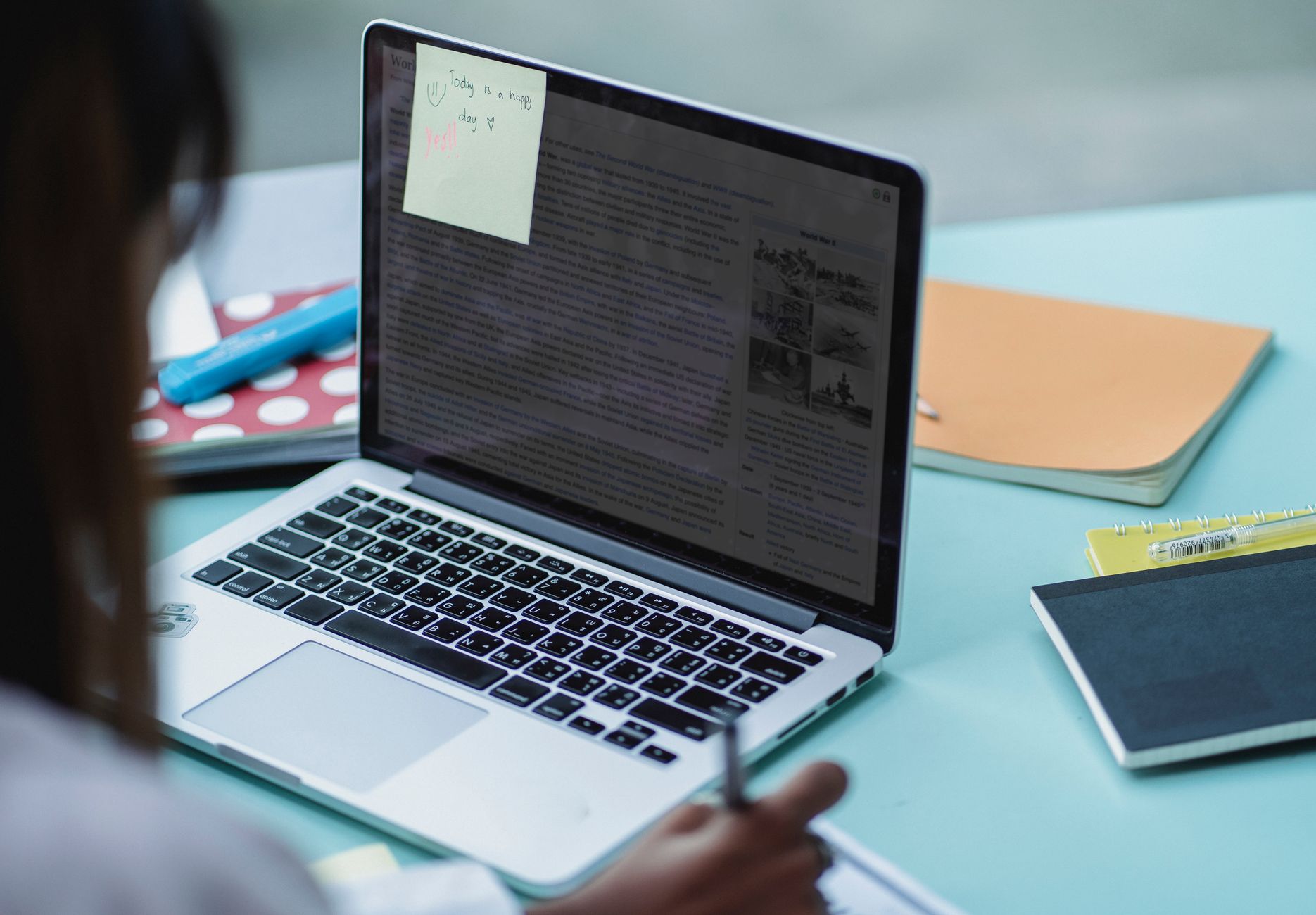 A small group looking together at a laptop screen with notes, writing on paper nearby.